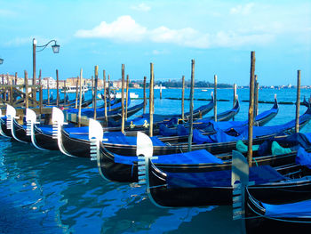 Gondolas moored on canal against sky