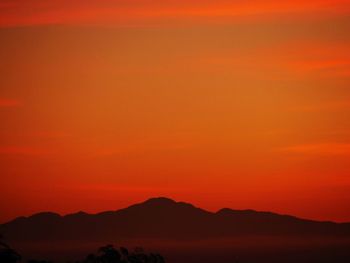 Scenic view of silhouette mountains against orange sky