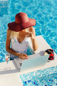 Rear view of woman wearing hat at poolside