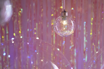 Close-up of illuminated lighting equipment hanging on glass