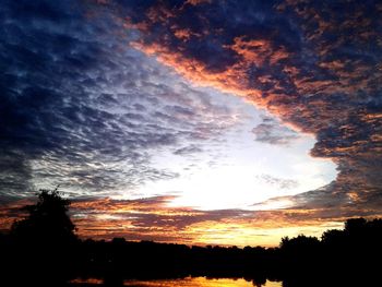 Low angle view of dramatic sky over silhouette landscape