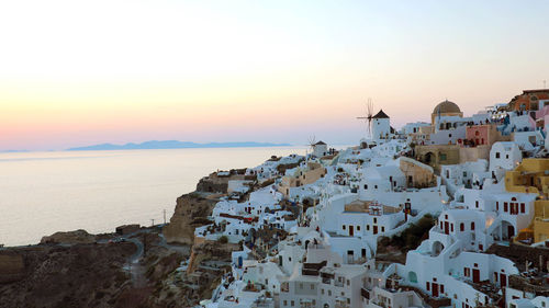 High angle view of buildings by sea against sky during sunset