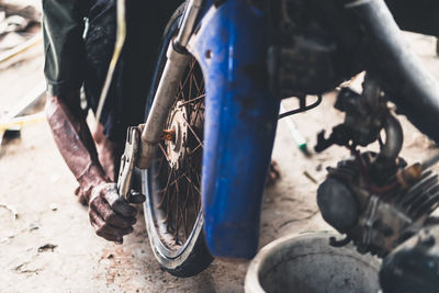Low section of man repairing motorcycle on road