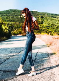 Full length side view of young woman standing on road