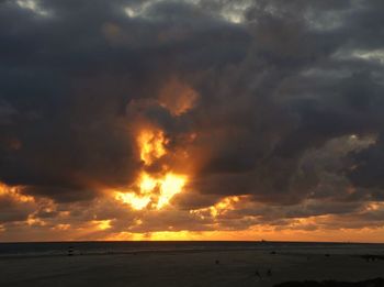 Scenic view of sea against dramatic sky during sunset