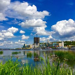 Built structure by river against cloudy sky