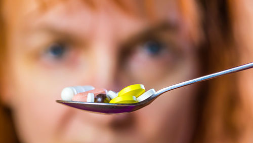 Close-up portrait of woman looking at pills in spoon