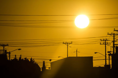 Low angle view of electricity pylon at sunset