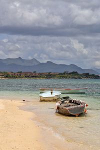 Boat moored on beach against sky