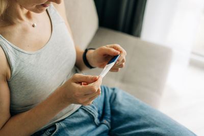 Unrecognizable woman checking pregnancy test, waiting for test result.