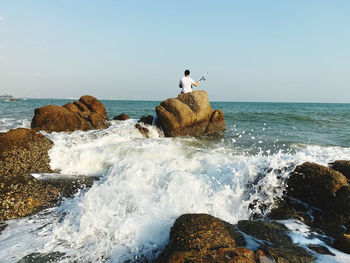 View of rocks in sea against clear sky