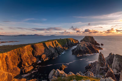 Scenic view of cliffs and sea against sky during sunset