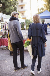 Rear view of young couple with leafy vegetables at market