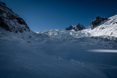 Scenic view of snowcapped mountains against clear blue sky