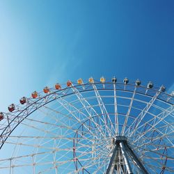 Low angle view of ferris wheel against clear blue sky