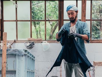 Man holding clothing while standing in shed