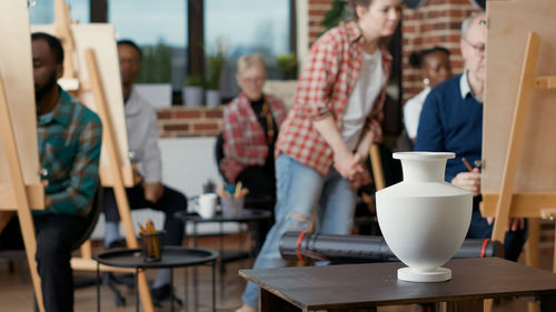 Vase in on table and student drawing it in art classroom