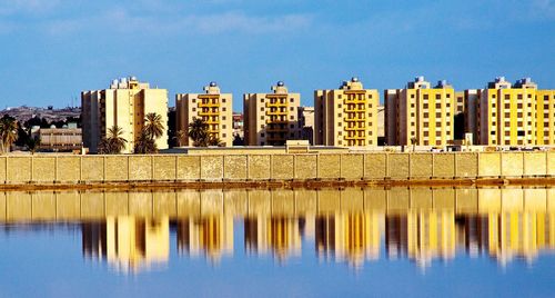 Reflection of buildings in lake against blue sky