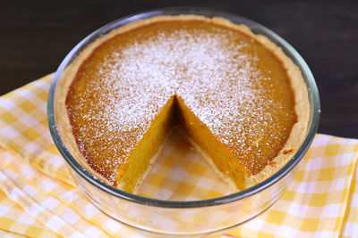 Closeup fresh baked and partly cut homemade pumpkin pie sprinkled with icing sugar