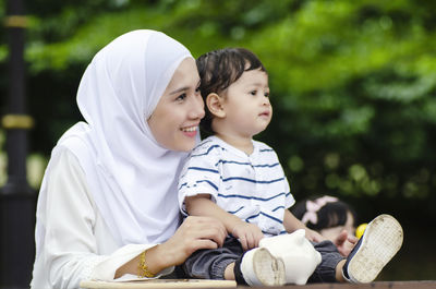 Mother and son holding piggy bank on table