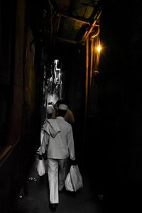 Rear view of people standing in illuminated dark room