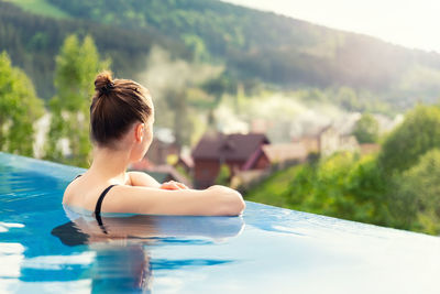 Rear view of woman relaxing in swimming pool