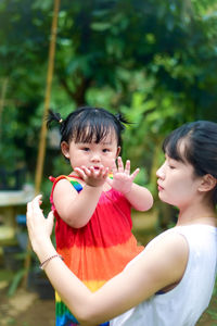 Mother carrying daughter at park