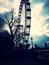 Low angle view of ferris wheel against cloudy sky