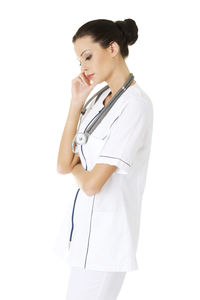 Thoughtful nurse standing against white background