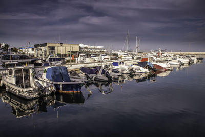 Boats moored at harbor against sky