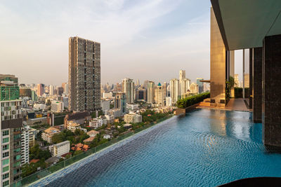 Buildings by swimming pool against sky in city