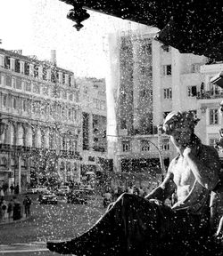 Woman sitting by buildings in city