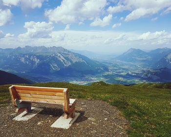 Empty bench on mountains against sky