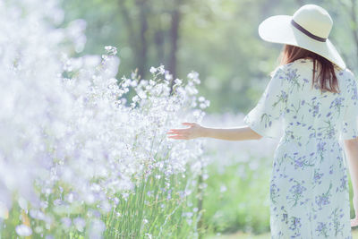 Midsection of woman standing by flowering plants