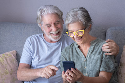 Man holding smart phone while sitting on sofa