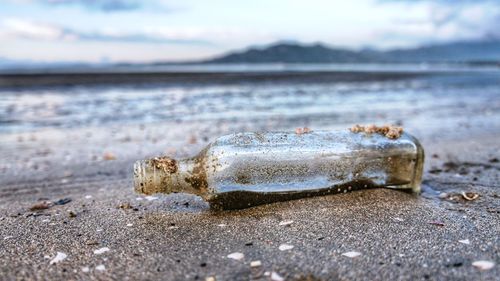 Close-up of bottle on beach against sky