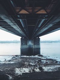 Low angle view of bridge over frozen river during winter