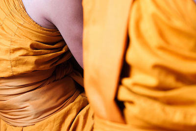 Midsection of monks wearing traditional clothing while sitting in temple