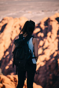 Rear view of woman standing on rock against sky during sunset