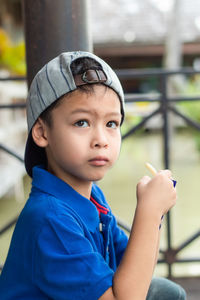 Boy looking away while sitting against railing