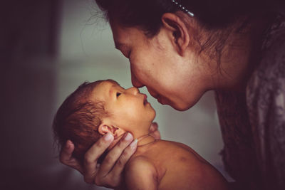 Side view of mother rubbing nose with baby boy at home