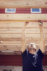 Man measuring plank while standing in yard