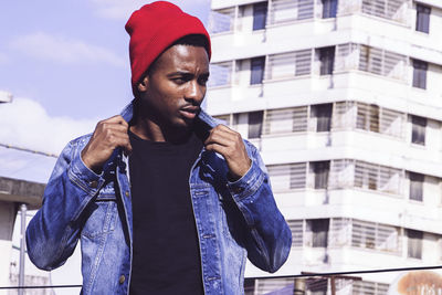 Man looking away while standing against building in city