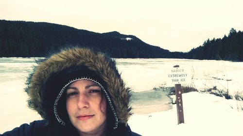 Close-up of woman wearing fur hood against frozen lake