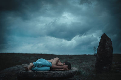 Man lying down on land against sky