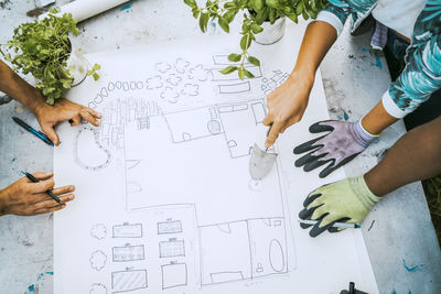 High angle view of male and female environmentalists pointing at drawing over table