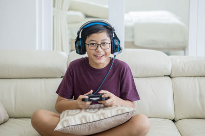 Portrait of boy playing video game while sitting on sofa at home