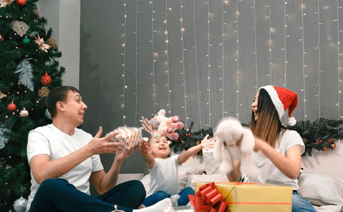 Side view of woman holding christmas tree at home