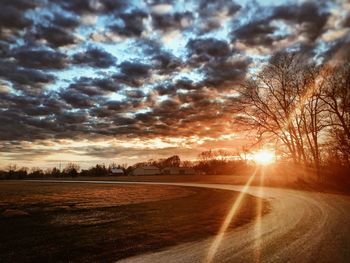 Scenic view of landscape against cloudy sky at sunset