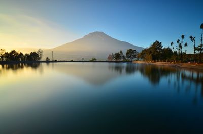 Scenic view of lake against mountains and sky during sunset